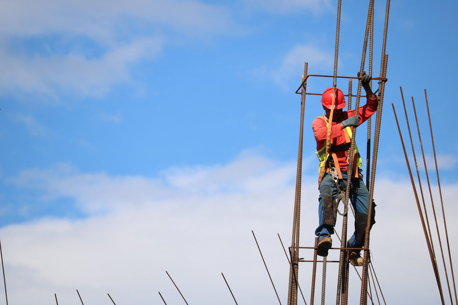A construction worker fixing steel reinforcement against a blue sky
